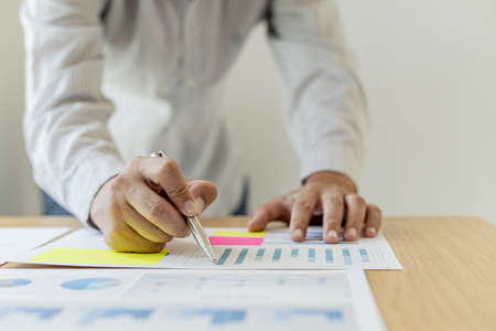 The sales manager is checking the monthly employee sales data for accuracy before paying the commission, he points to the document displayed in the form of a chart. The concept of paying commissions.の写真素材