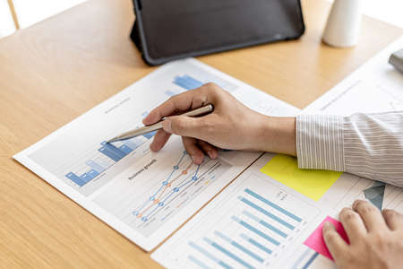The financial officer uses a pen to point at the numbers on the financial documents to verify the correctness before submitting the information in the documents to the meeting. Finance concept.の写真素材