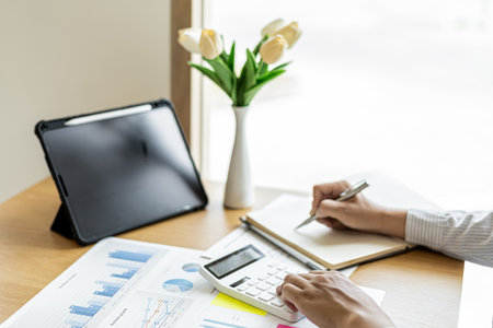 The financial officer presses the calculator to check the information recorded in the book for accuracy before submitting the information in the document to the meeting. Finance concept.の写真素材