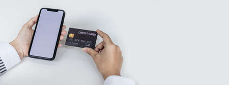 Woman holding a smartphone and a credit card, she is filling out her credit card information to pay for the purchases made through the smartphone app. Online shopping and credit card payment concept.の写真素材