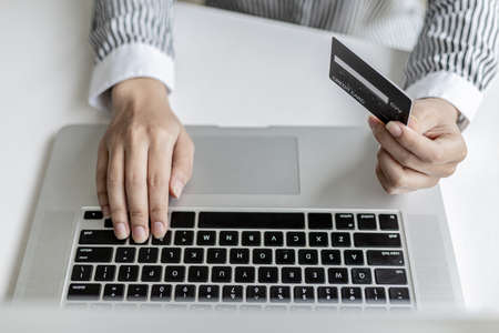 Woman holding credit card and typing on a laptop keyboard, she is filling out credit card information to pay for an order on an internet shopping site. Online shopping and credit card payment conceptの写真素材