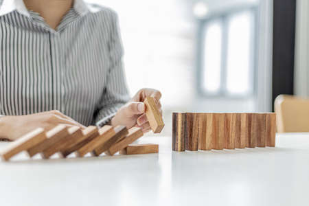 A woman is holding wooden blocks in a row, she grabs the center piece to complete them, the wooden...