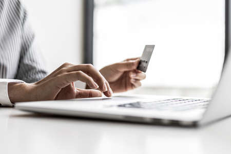 Woman holding credit card and typing on a laptop keyboard, she is filling out credit card information to pay for an order on an internet shopping site. Online shopping and credit card payment conceptの写真素材