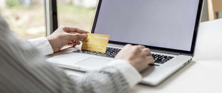 Woman holding credit card and typing on a laptop keyboard, she is filling out credit card information to pay for an order on an internet shopping site. Online shopping and credit card payment conceptの写真素材