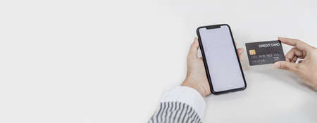 Woman holding a smartphone and a credit card, she is filling out her credit card information to pay for the purchases made through the smartphone app. Online shopping and credit card payment concept.の写真素材