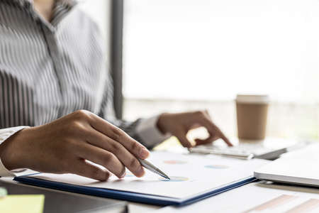 Businesswoman's hand holding a pen pointing at a bar chart on a corporate financial information...
