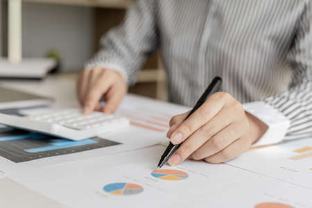 Businessman working in a private office, she is reviewing the company's financial documents sent from the finance department before he takes it to a meeting with a business partner. Financial concept.の写真素材