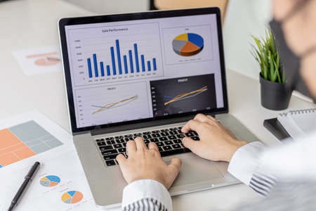 A businesswoman typing on a laptop keyboard, she is preparing a financial summary to bring to a meeting with business partners. Concept of company financial management. Checking financial information.の写真素材