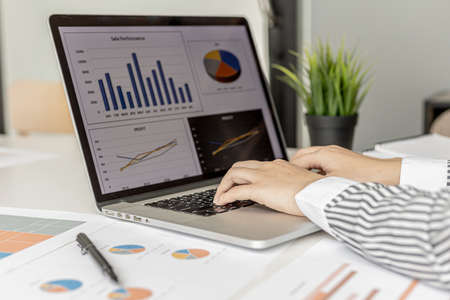 A businesswoman typing on a laptop keyboard, she is preparing a financial summary to bring to a meeting with business partners. Concept of company financial management. Checking financial information.の写真素材