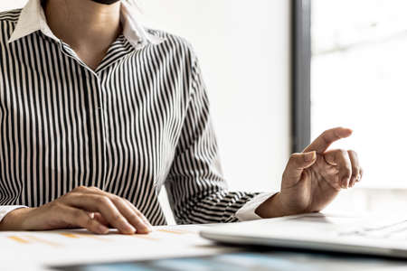 A businesswoman using a laptop, she is preparing a financial summary to bring to a meeting with...