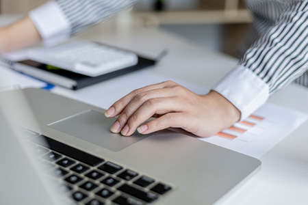 Close-up A businesswoman working in a private room, She is using a touchpad on her laptop, she uses a messenger to chat with a partner. Concept of using technology in communication.の写真素材