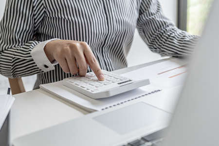 Businessman working in a private office, she is reviewing the company's financial documents sent...