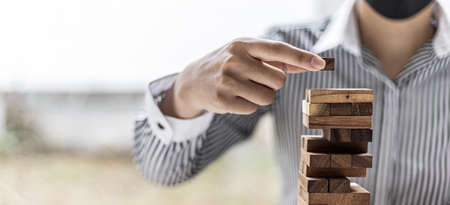 A woman is pulling a block of wood from a row and not breaking it down, like running a good business...