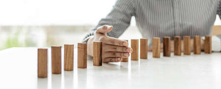 Women put their hands between wooden blocks, wooden blocks arranged in dominoes, likened to running...