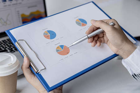 Businesswoman's hand holding a pen pointing at a bar chart on a corporate financial information...
