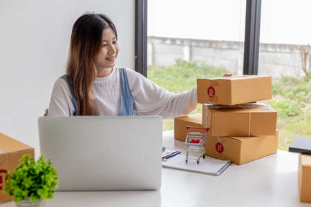 An online seller is counting the number of parcel boxes in preparation for shipping to customers, brown parcel boxes tied with ropes to avoid damage. Online shopping concept.の写真素材