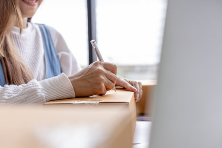 Online merchants are writing customer shipping information on the front of the parcel box, packing the goods in a parcel box and sending it through a private transport company. Online shopping conceptの写真素材