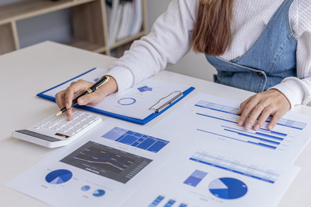 Woman holding a pen pointing to documents on a desk, she is a financial scholar, she is checking...