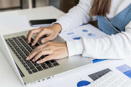 A businesswoman typing on a laptop, she is talking to an employee using a laptop messenger to...