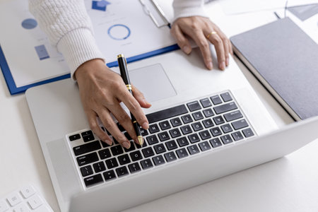 A businesswoman typing on a laptop, she is talking to an employee using a laptop messenger to inquire about company finances. The concept of using technology to assist in communication.の写真素材