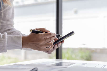 businesswoman holding a mobile phone, she is looking at information on mobile phone that the...