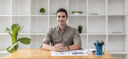 Portrait of a handsome man sitting in the office. A new generation of businessman founded a startup company and managed to grow their business quickly. Business portrait concept.の写真素材