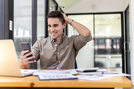 Young businessman is video call with business partner using smartphone, he talks with friends to discuss marketing plans to increase sales for the company. Concept of using technology in communicationの写真素材