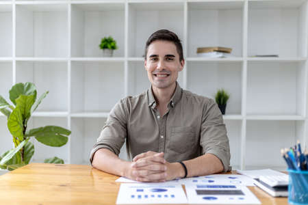 Portrait of a handsome man sitting in the office. A new generation of businessman founded a startup company and managed to grow their business quickly. Business portrait concept.の写真素材