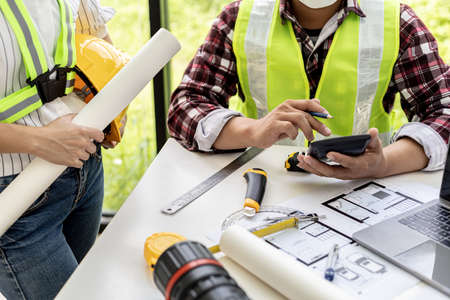 Architect engineers are using the phone at the meeting to discuss construction materials, they meet together to plan the construction and fix some designs. Design and interior design ideas.の写真素材