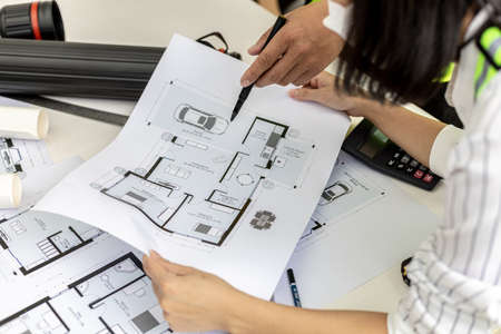 Architect engineers are standing by to look at the blueprints of the designed houses, they meet together to plan the construction and modify some of the designs. Design and interior design ideas.の写真素材