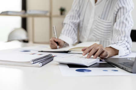 A business finance woman is reviewing a company's financial documents prepared by the Finance Department for a meeting with business partners. Concept of validating the accuracy of financial numbers.の写真素材