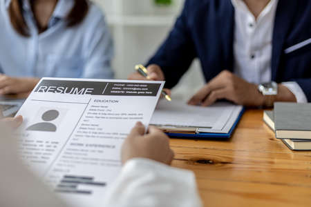 The atmosphere of the interview room in the start-up company, the applicant is handing the resume to the interviewer as a supporting document for the interview, two interviewers. Job interview conceptの写真素材