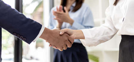 Close-up two business men holding hands, Two businessmen are agreeing on business together and shaking hands after a successful negotiation. Handshaking is a Western greeting or congratulation.の写真素材