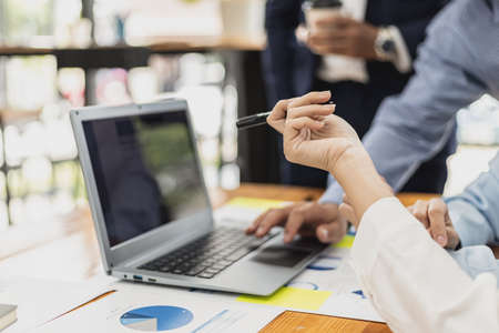 A female employee holding a pen and pointing at a laptop screen, she is attending a meeting with the management team to finalize the company's financial reports. Startup company meeting concept.の写真素材