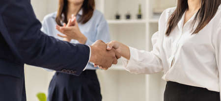 Close-up two business men holding hands, Two businessmen are agreeing on business together and shaking hands after a successful negotiation. Handshaking is a Western greeting or congratulation.の写真素材