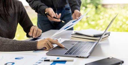 The conference room has two businessmen meeting together, one businessman using a laptop and the...