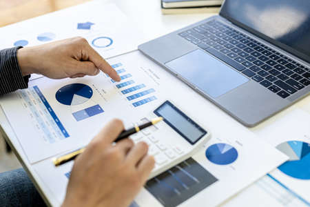 Businessman presses a calculator to calculate numbers on financial documents, he checks the accuracy of the financial statements to bring to a meeting with his partner. Concept of financial managementの写真素材