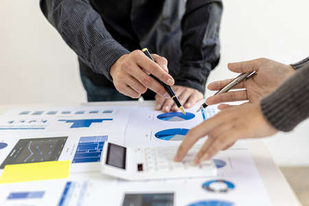 A conference room where executives and marketers are looking at sales documents to analyze, plan...