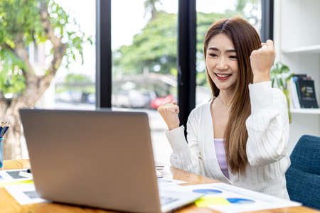 Beautiful young Asian woman gesturing in front of a laptop, concept image of Asian business woman working smart, modern female executive, startup business woman, business leader woman.の写真素材
