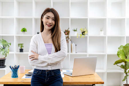 Portrait of a young beautiful Asian woman standing in a white office room, concept image of Asian business woman, modern female executive, startup business woman, business leader woman.の写真素材