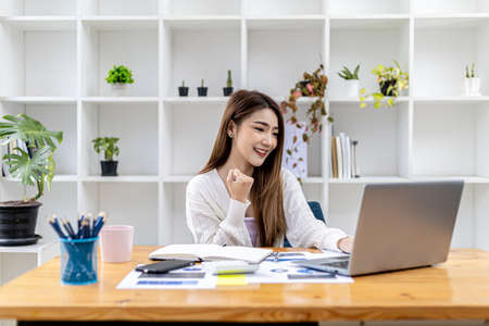Beautiful young Asian woman gesturing in front of a laptop, concept image of Asian business woman working smart, modern female executive, startup business woman, business leader woman.の写真素材