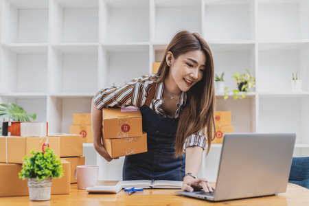 A beautiful Asian business owner opens an online store, she is checking orders from customers via...