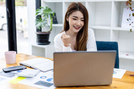 Beautiful young Asian woman gesturing in front of a laptop, concept image of Asian business woman working smart, modern female executive, startup business woman, business leader woman.の写真素材