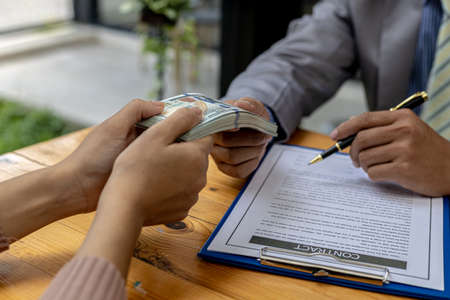 Picture of two people handing over a dollar, they are business partners who are doing corrupt...