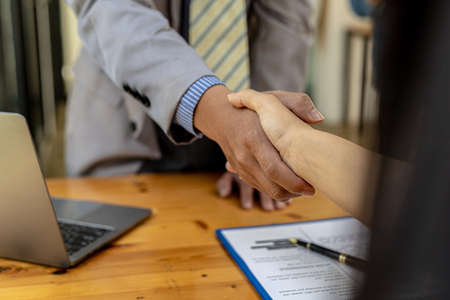 The job interviewer and the job applicant are holding hands after the job interview is finished. The concept of recruiting employees to work in the company, vacant positions.の写真素材