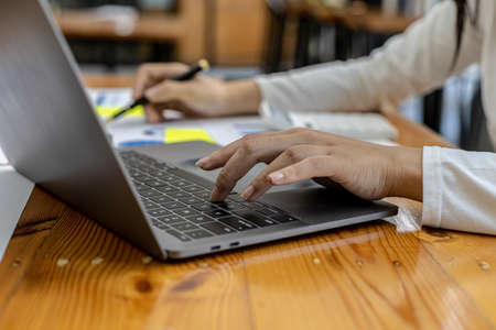 Close-up A business woman working in a private room, She is typing on a laptop keyboard, She uses a messenger to chat with a partner. Concept of using technology in communication.の写真素材