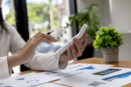 Close-up of a businesswoman using a white calculator, a financial businessman examining the...