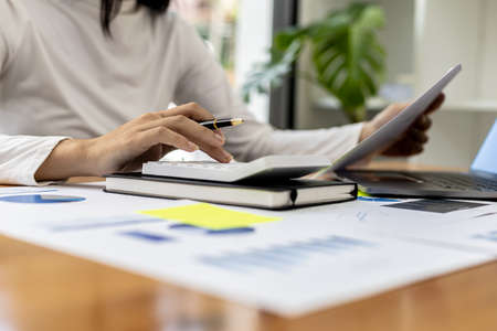 The company's finance manager is using a calculator, he uses a calculator to calculate the numbers in the company's financial documents that employees in the department create as meeting documents.の写真素材