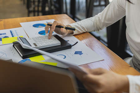 The company's finance manager is using a calculator, he uses a calculator to calculate the numbers in the company's financial documents that employees in the department create as meeting documents.の写真素材