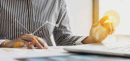 Businesswoman analyzing financial documents, she is looking at company financial data to analyze business risks. Graphic showing business growth chart. Business administration concept.の写真素材